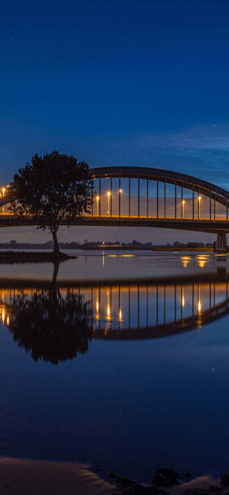 Telefoonachtergrond: lichtende nachtwolken boven de Lekbrug