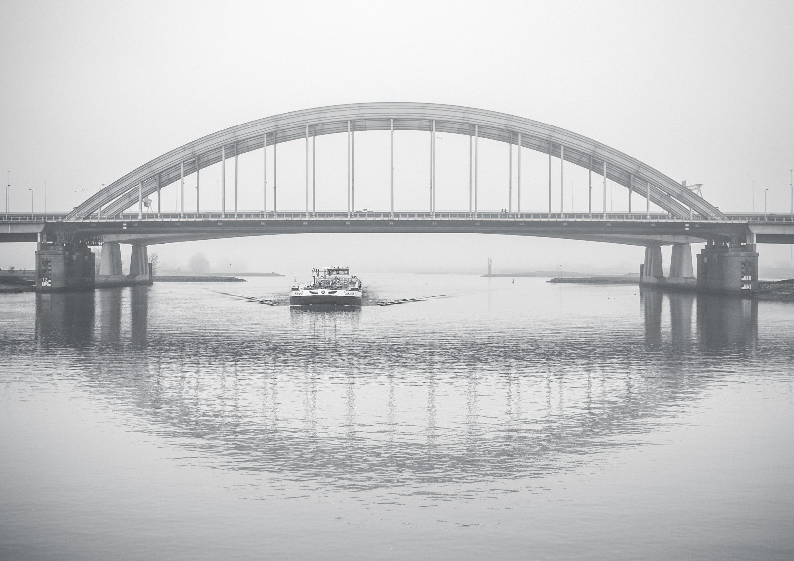 De oude Lekbrug als boogbrug in dichte mist, met een schip eronder