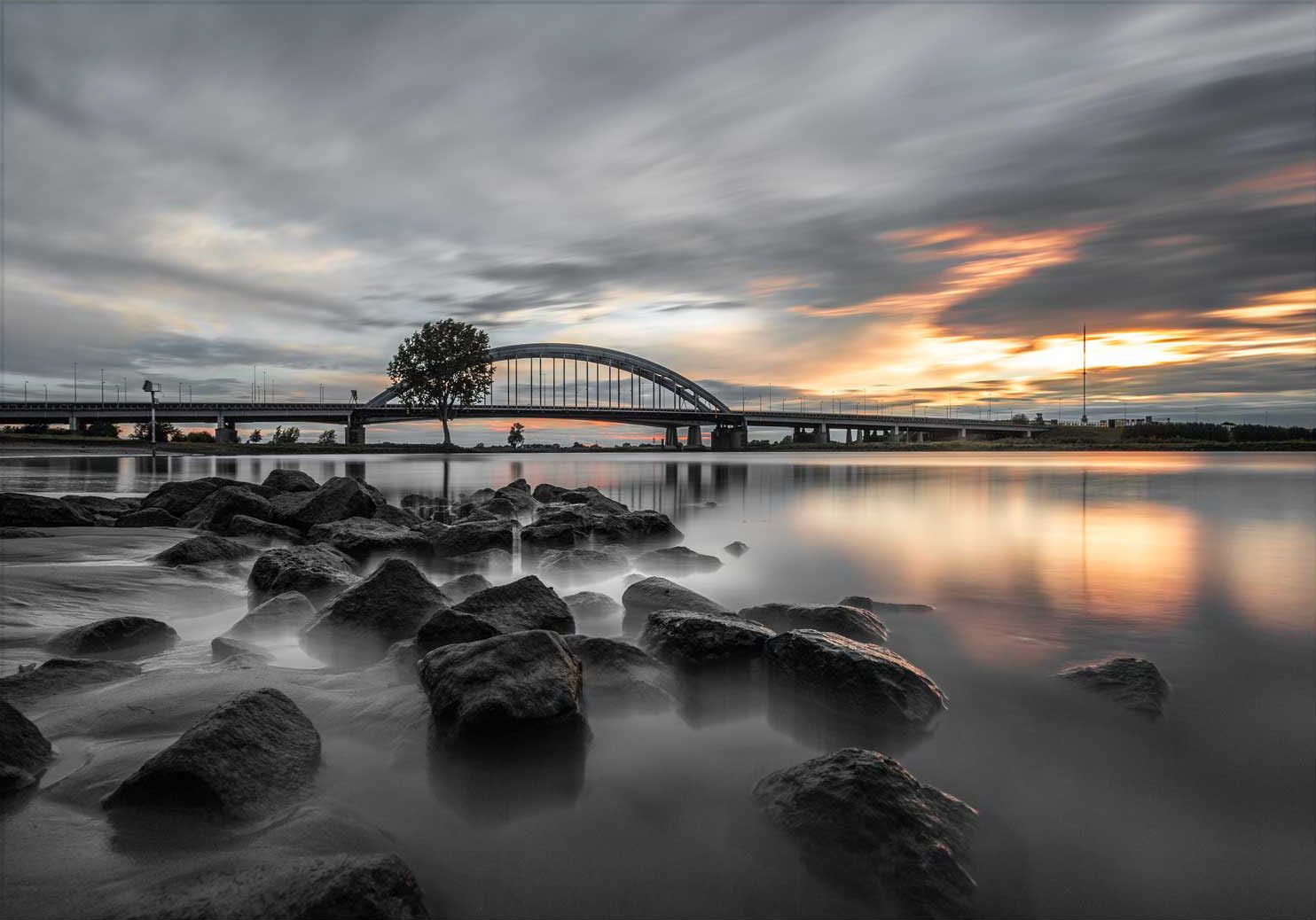 De oude Lekbrug onder een bewegende wolkenlucht, het water glad door de lange sluitertijd